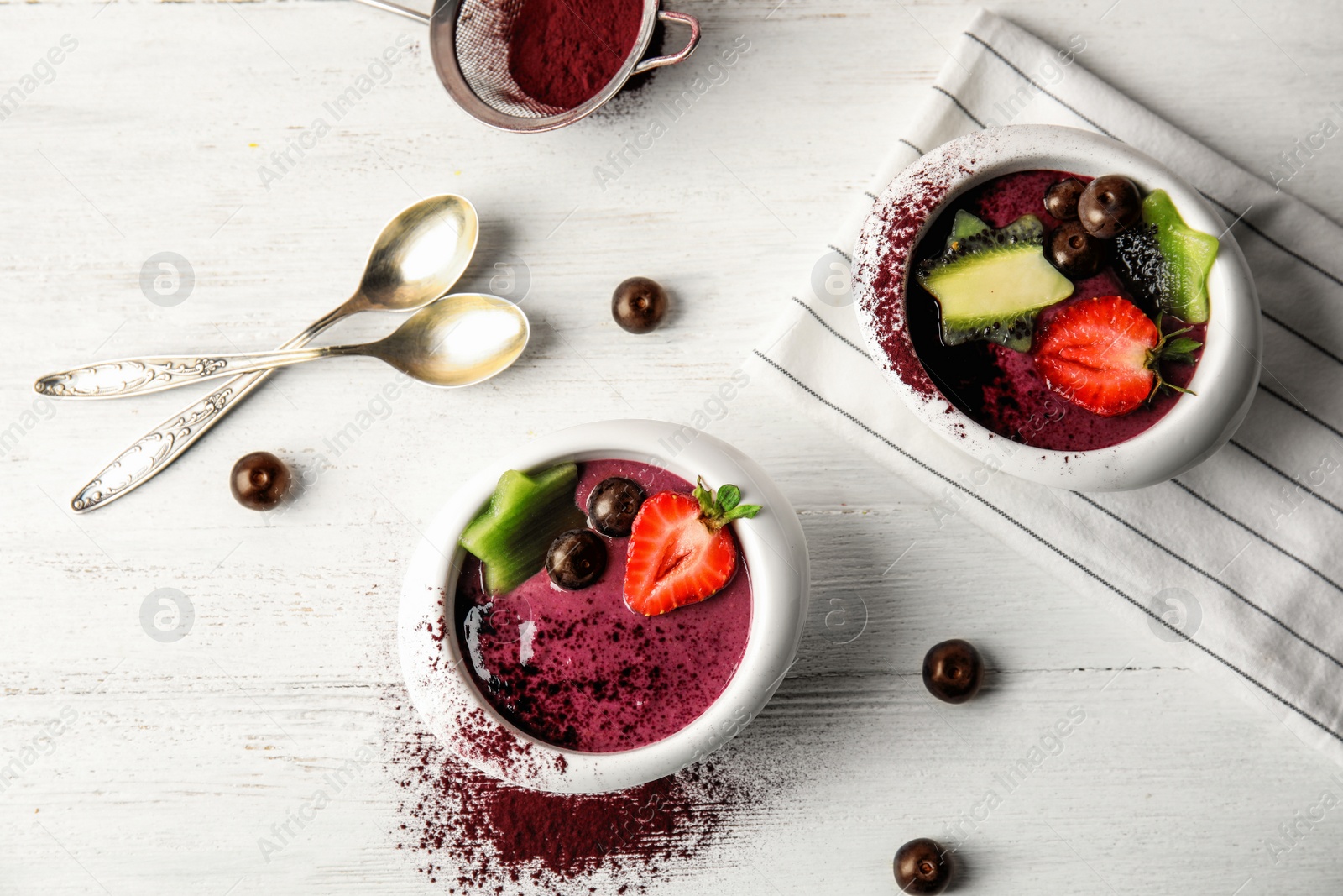 Photo of Flat lay composition with bowls of tasty acai smoothie on light table