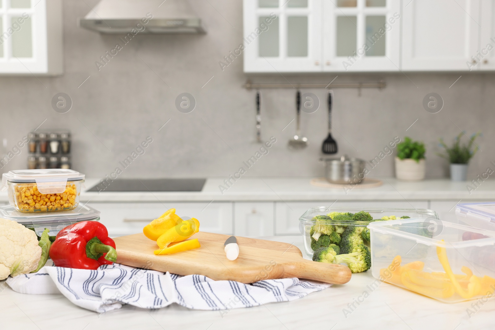 Photo of Containers with different fresh products, wooden board and knife on white marble table, space for text. Food storage