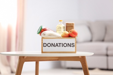 Photo of Donation box with food products on table indoors