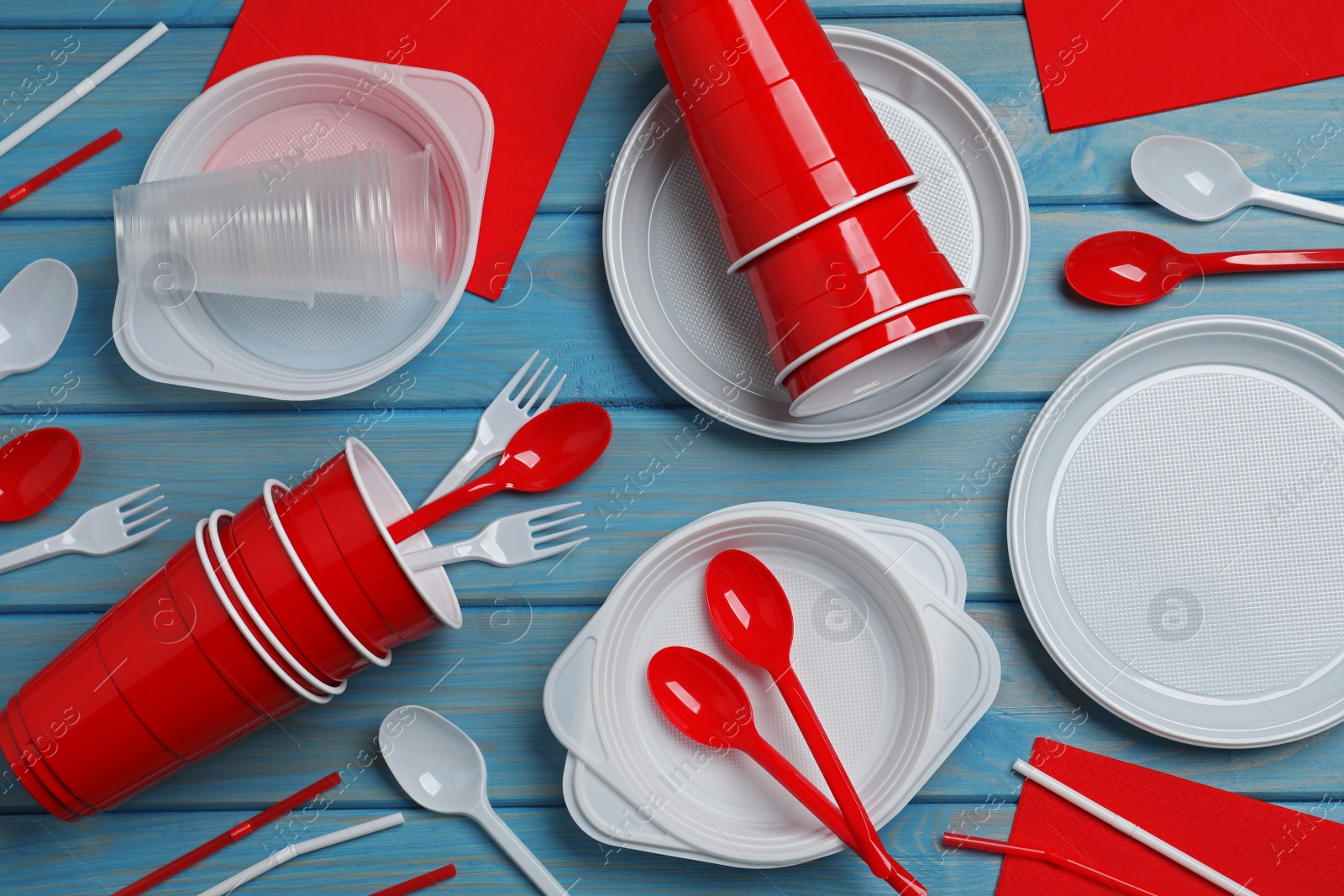 Photo of Disposable tableware on light blue wooden background, flat lay