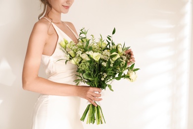 Photo of Young bride wearing wedding dress with beautiful bouquet on light background, closeup