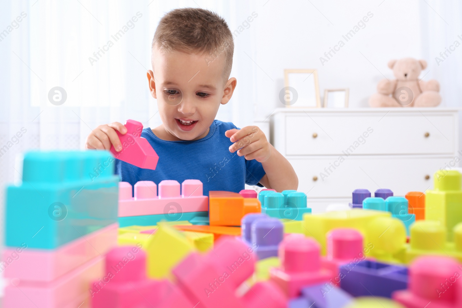 Photo of Cute little boy playing with colorful building blocks at table in room