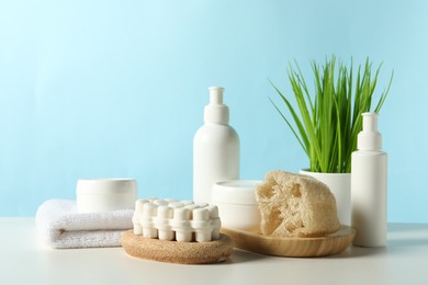 Photo of Different bath accessories and houseplant on white table against light blue background. Space for text