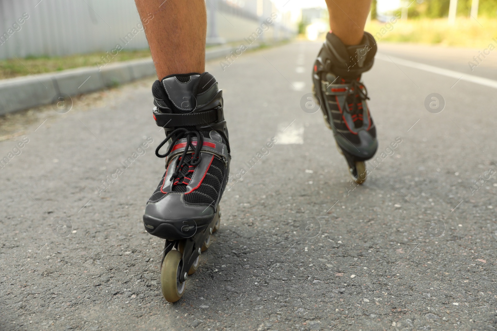 Photo of Young man roller skating outdoors, closeup. Recreational activity