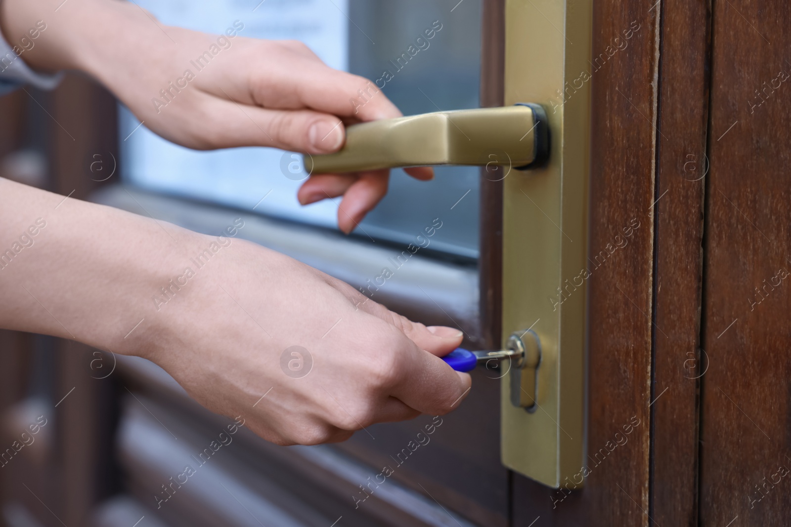 Photo of Woman opening door with key outdoors, closeup