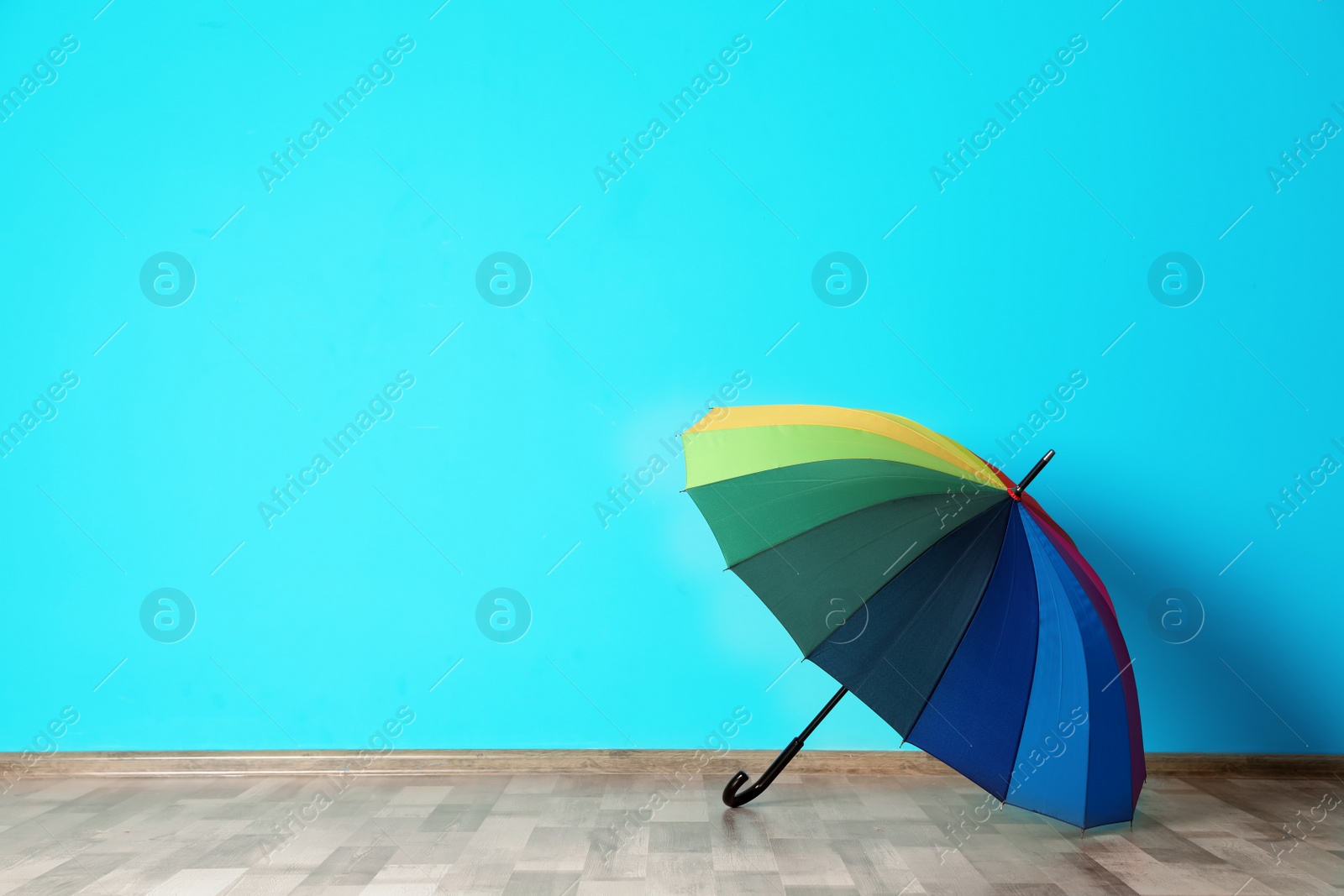 Photo of Beautiful open umbrella on floor near color wall with space for design