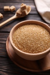 Bowl and spoon with brown sugar on wooden table