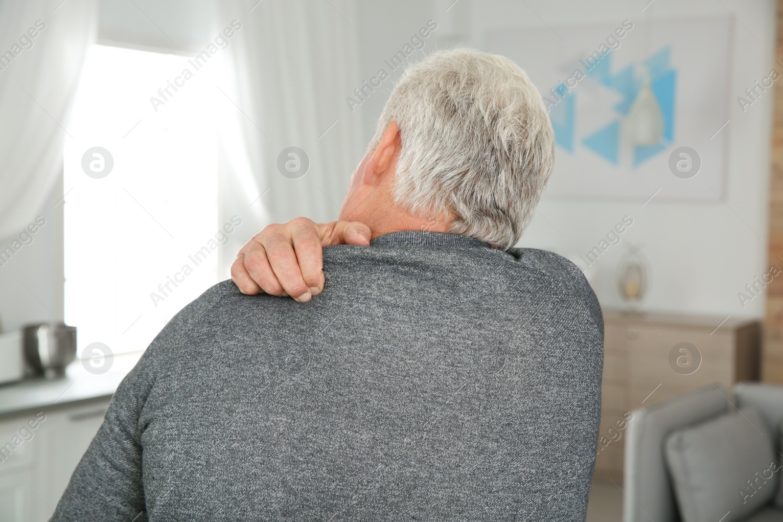 Photo of Mature man scratching back at home. Annoying itch