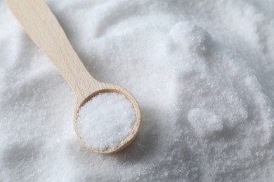 Photo of Wooden spoon on white sea salt, closeup. Space for text