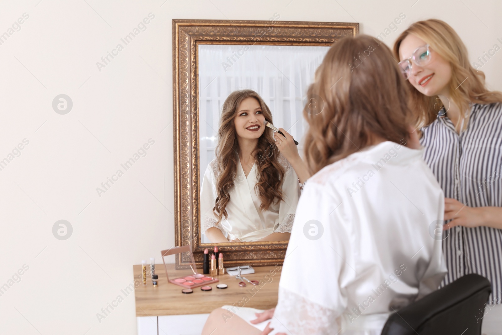 Photo of Professional makeup artist working with client in dressing room