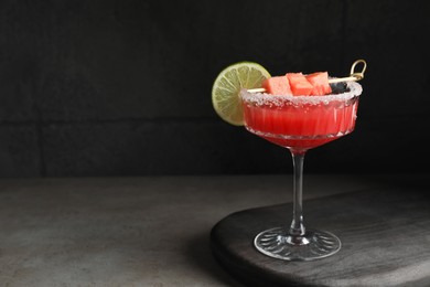 Photo of Cocktail glass of delicious fresh watermelon juice with lime on grey table. Space for text
