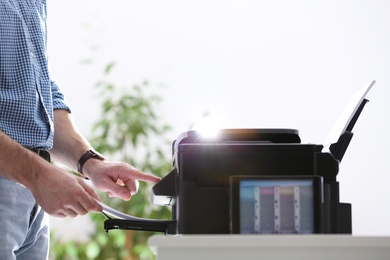 Photo of Employee using modern printer in office, closeup