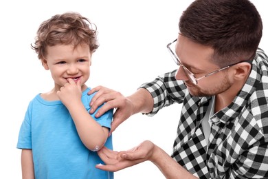 Father applying ointment onto his son`s elbow on white background