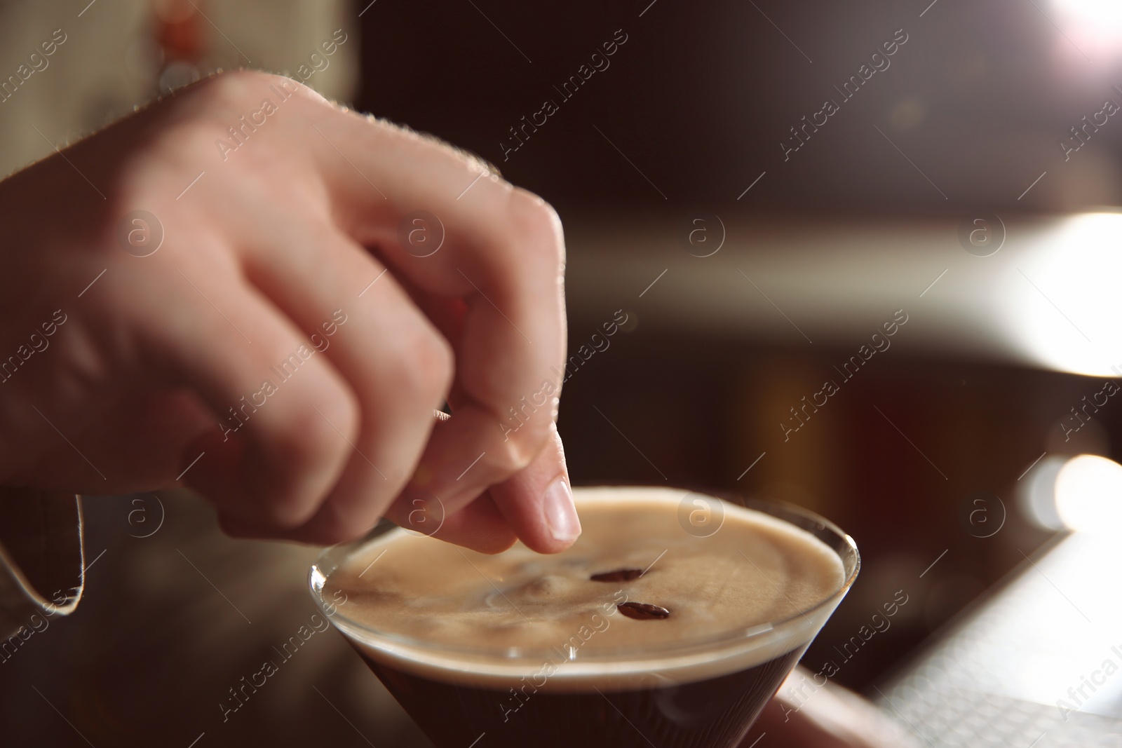 Photo of Barman adding coffee bean to martini espresso cocktail, closeup. Space for text