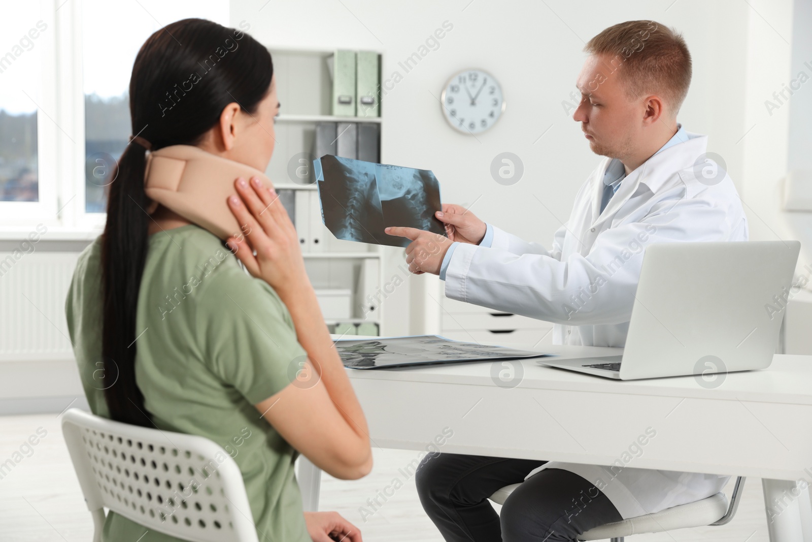 Photo of Doctor with neck MRI image consulting patient in clinic