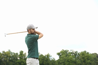 Photo of Man playing golf against blue sky. Space for text
