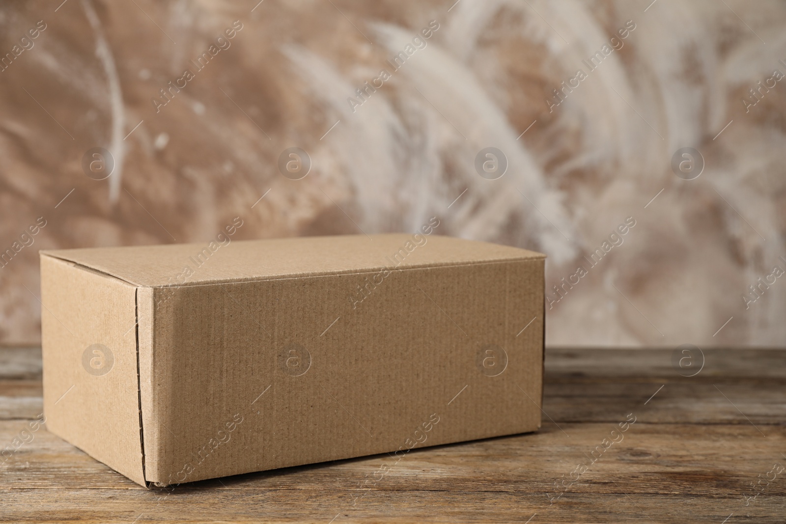 Photo of Closed cardboard box on wooden table against brown background