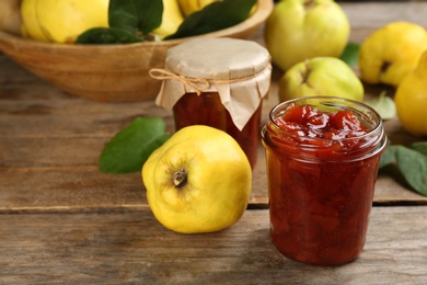 Photo of Delicious quince jam and fruits on wooden table, closeup