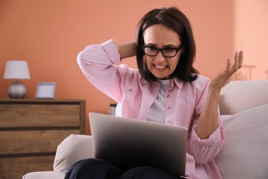 Photo of Emotional woman with laptop at home. Online hate concept