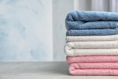Photo of Stack of soft bath towels on table against blurred background. Space for text