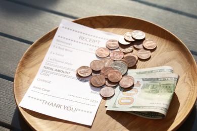 Photo of Wooden plate with payment for order and receipt on table, closeup. Leave tip