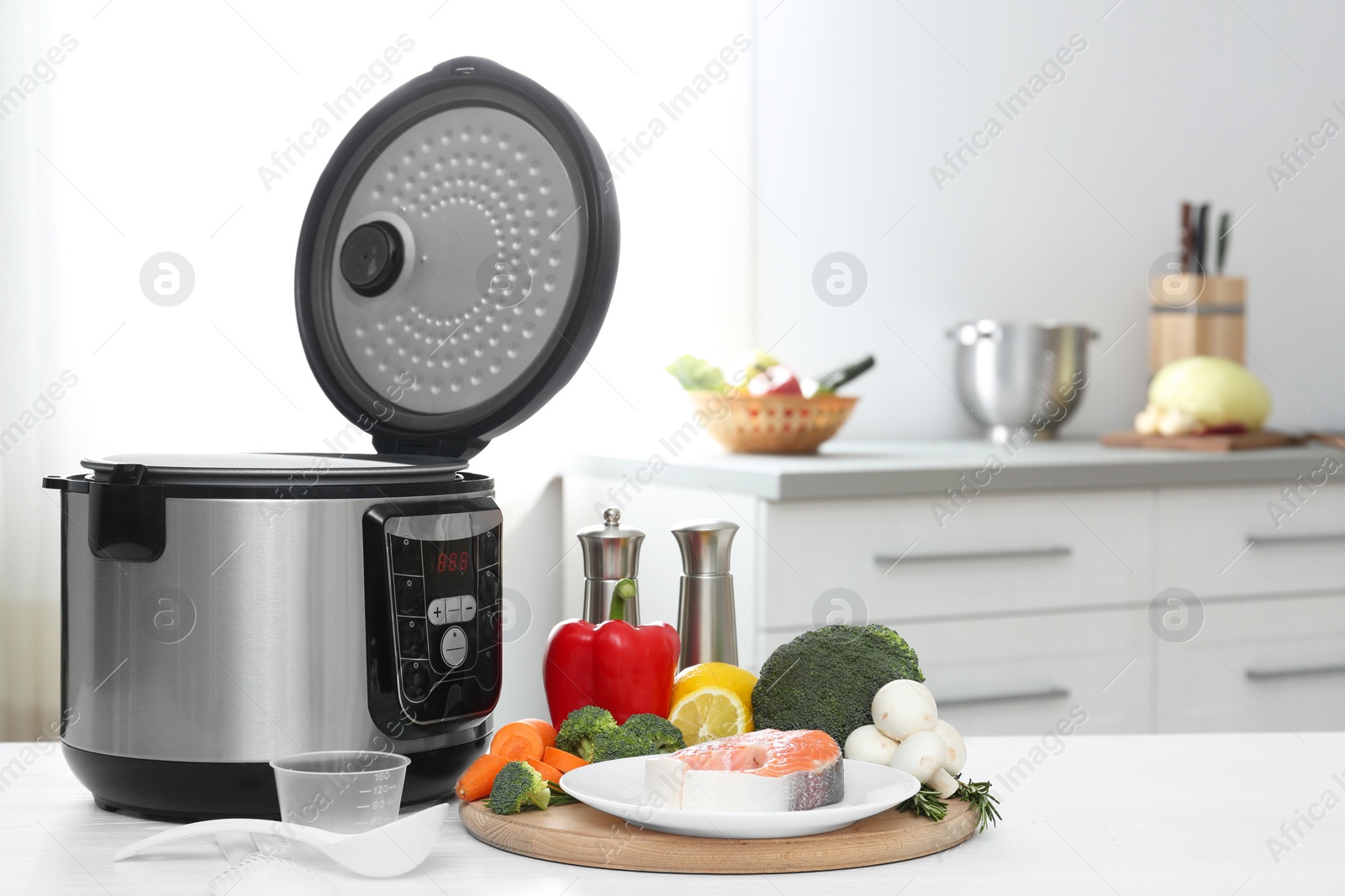 Photo of Modern multi cooker and products on table in kitchen. Space for text