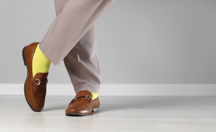 Man wearing stylish shoes and yellow socks indoors, closeup. Space for text