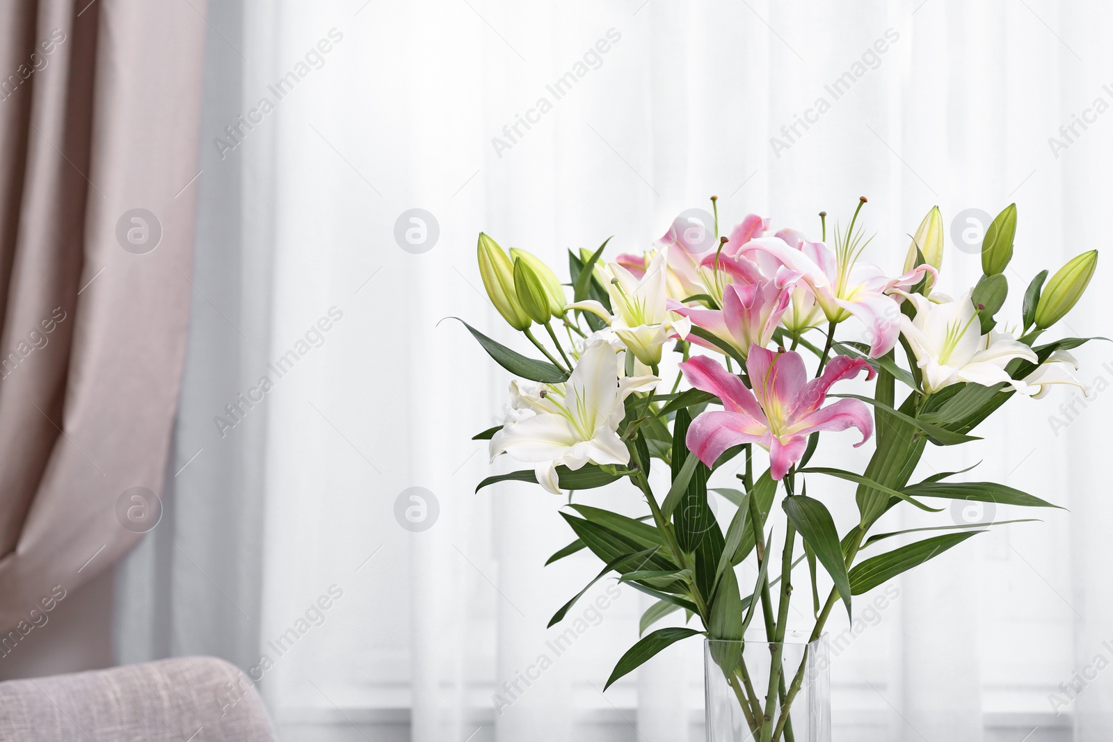 Photo of Vase with bouquet of beautiful lilies on blurred background. Space for text