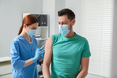 Doctor giving hepatitis vaccine to patient in clinic