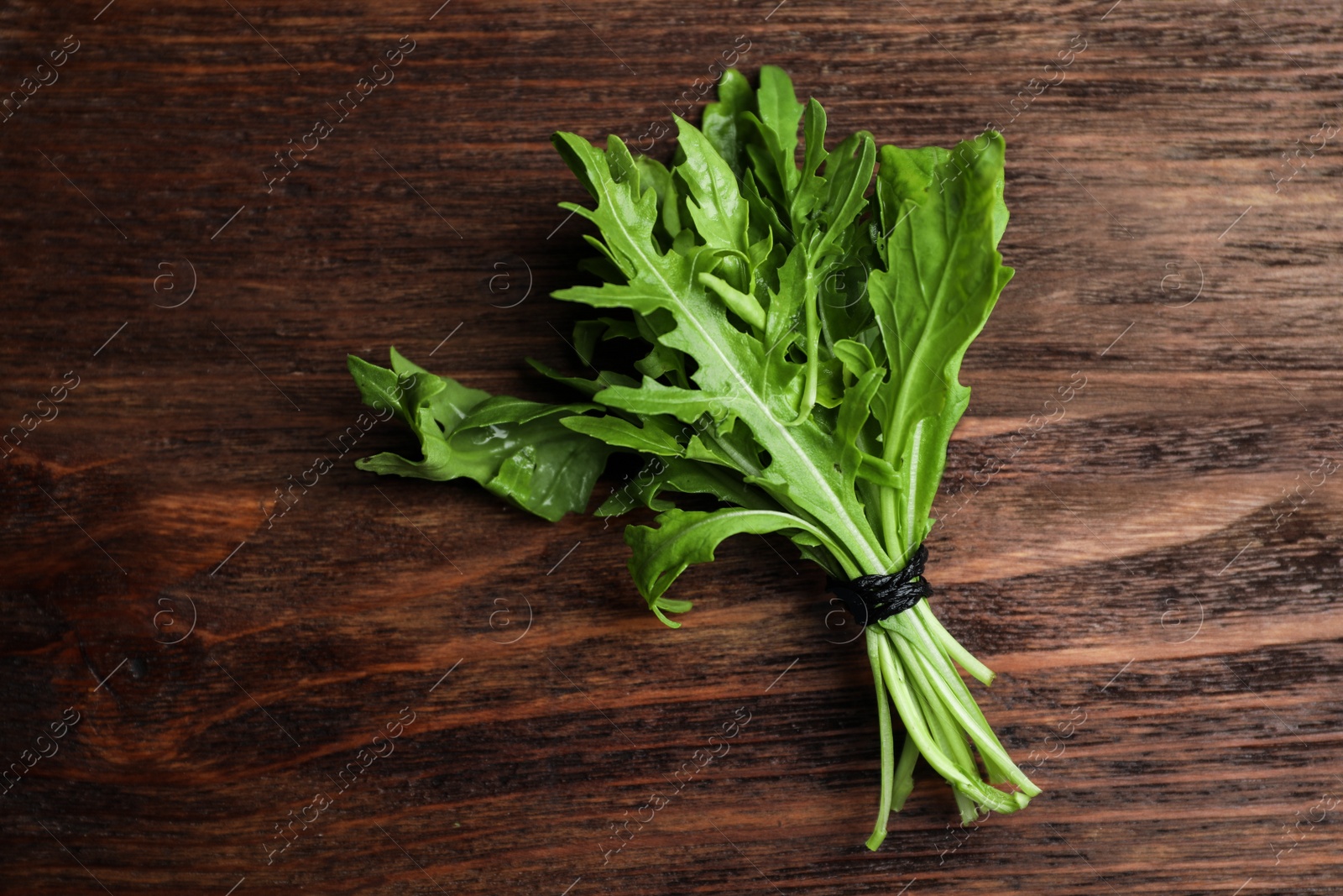 Photo of Fresh arugula on wooden table, top view