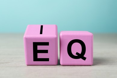Pink cubes with letters E, I and Q on table