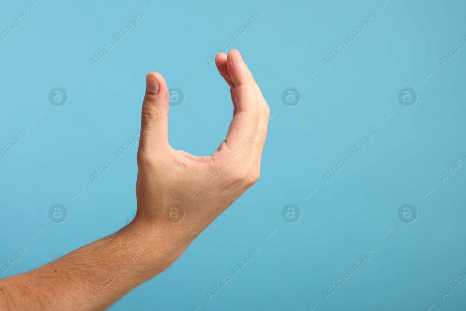 Photo of Man holding something in hand on light blue background, closeup. Space for text