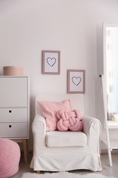 Pillows on light armchair in room interior. Unusual cushion design