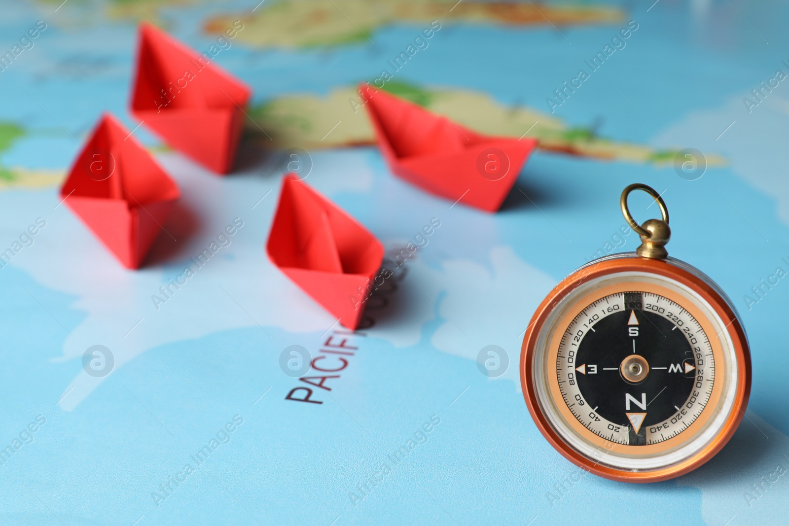 Photo of Bright paper boats and compass on world map