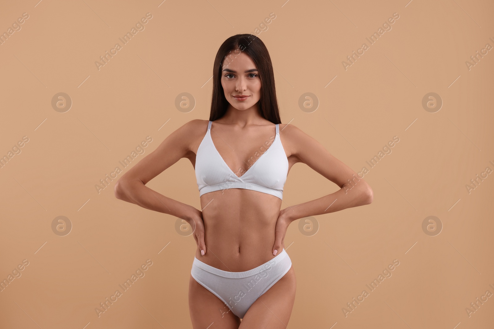 Photo of Young woman in stylish white bikini on beige background