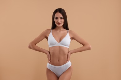 Photo of Young woman in stylish white bikini on beige background
