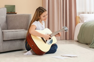 Photo of Teenage girl playing acoustic guitar in room