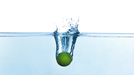 Photo of Lime falling down into clear water against white background