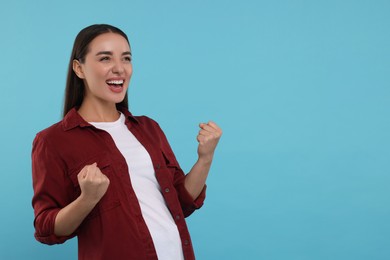 Photo of Happy sports fan celebrating on light blue background, space for text