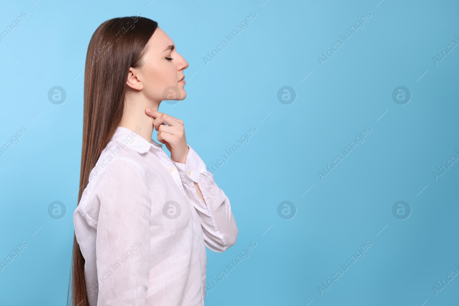 Photo of Young woman with sore throat on light blue background. Space for text