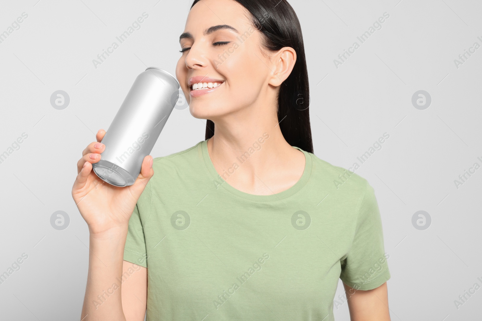 Photo of Beautiful happy woman drinking from beverage can on light grey background