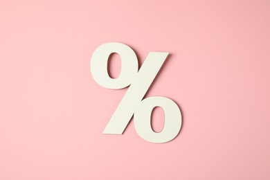 Photo of White percent sign on pink background, top view