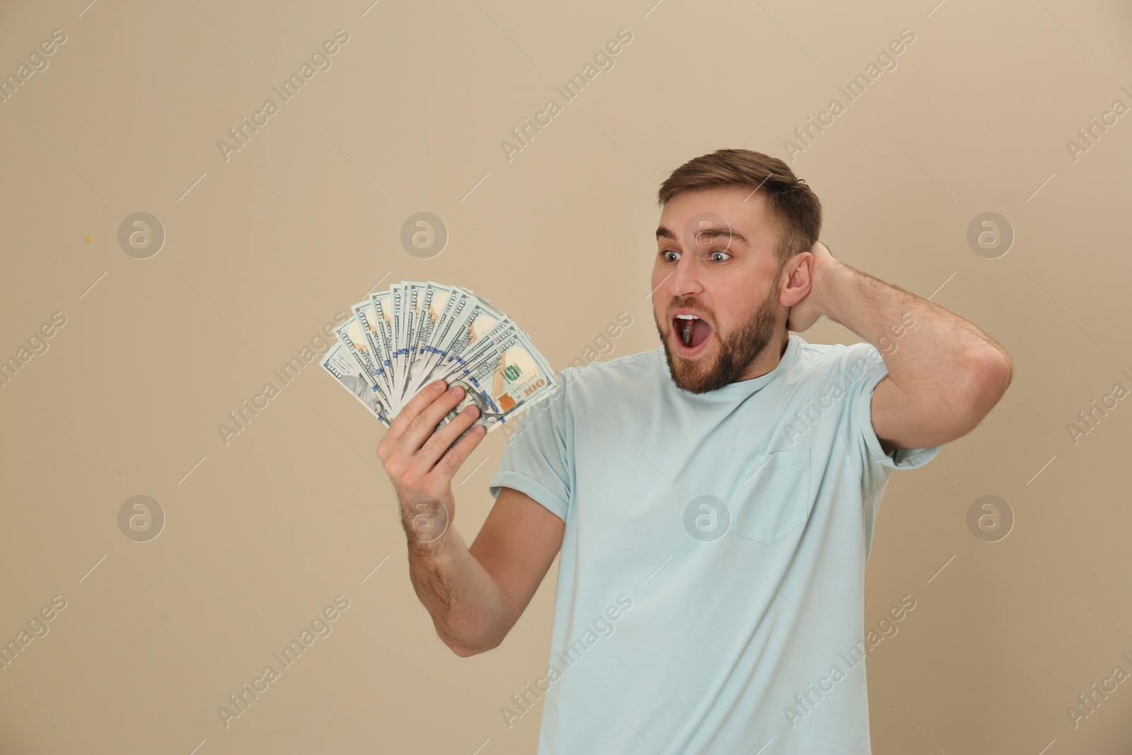 Photo of Portrait of emotional young man with money on color background