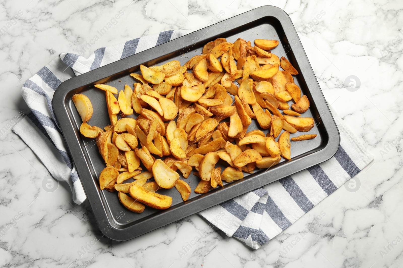 Photo of Sheet pan with delicious oven baked potatoes on marble background, flat lay