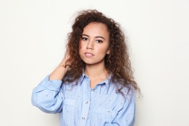 Young African-American woman with beautiful face on light background