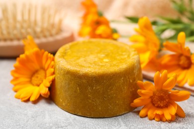 Photo of Yellow solid shampoo bar and flowers on light table, closeup. Hair care