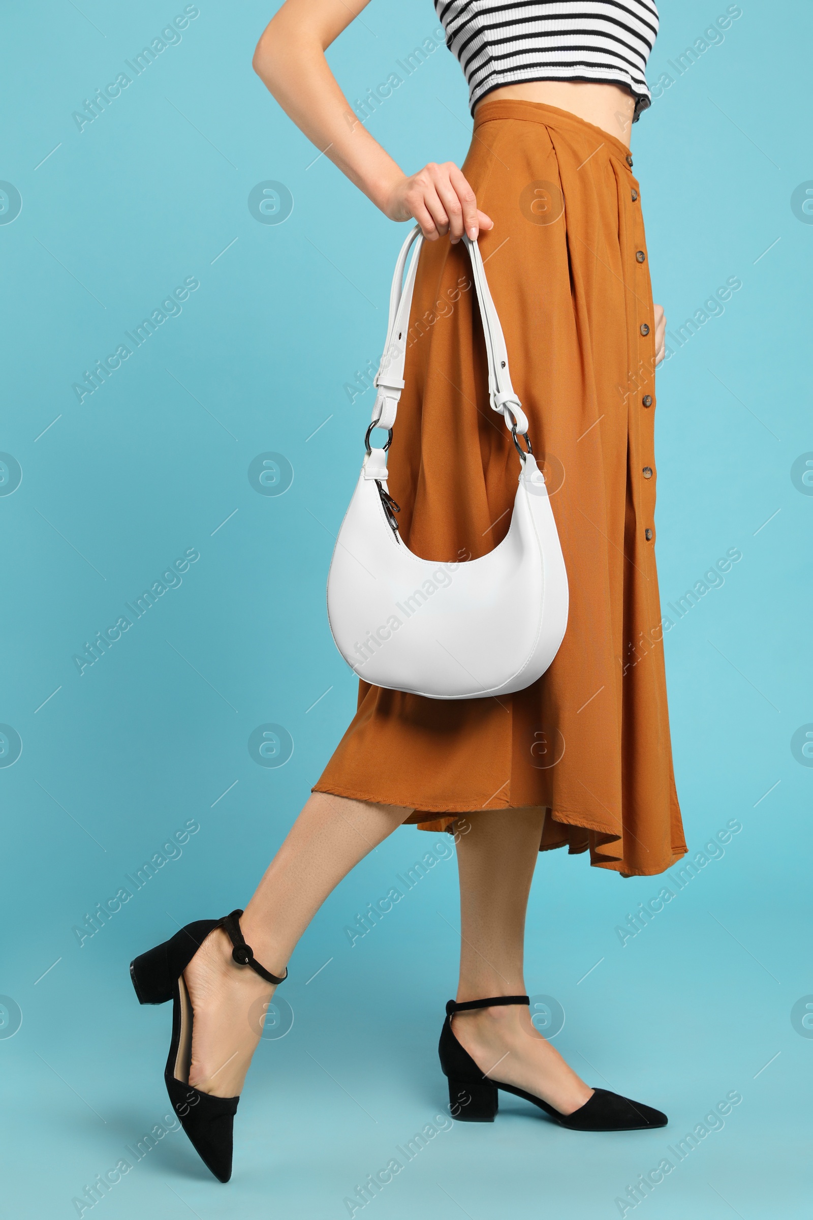 Photo of Stylish woman with trendy baguette bag on turquoise background, closeup