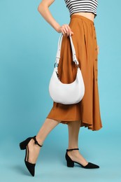 Photo of Stylish woman with trendy baguette bag on turquoise background, closeup