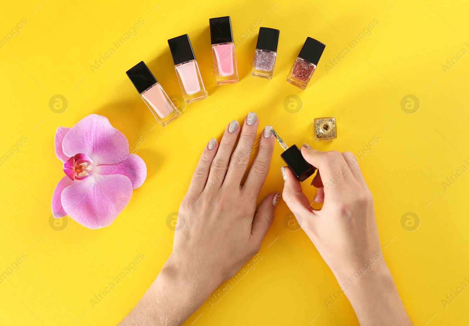 Photo of Woman applying nail polish on color background, top view