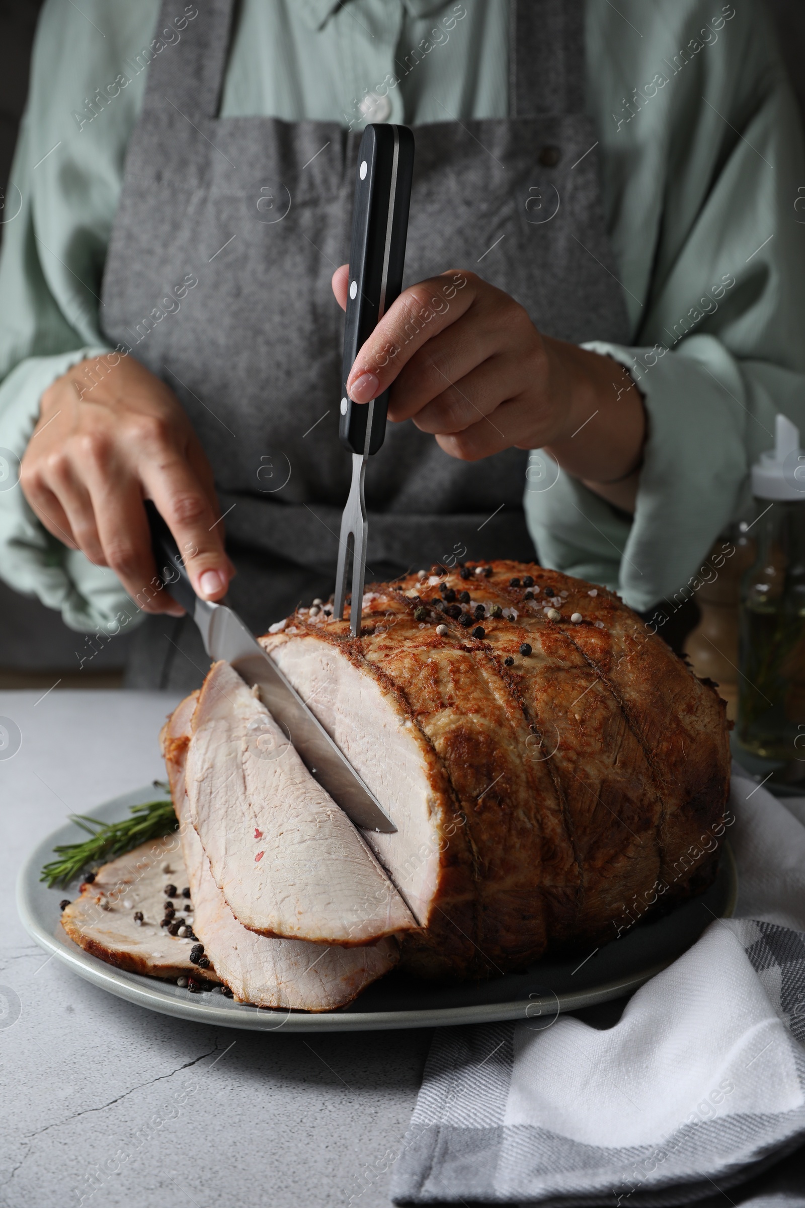 Photo of Woman cutting delicious baked ham at wooden table, closeup